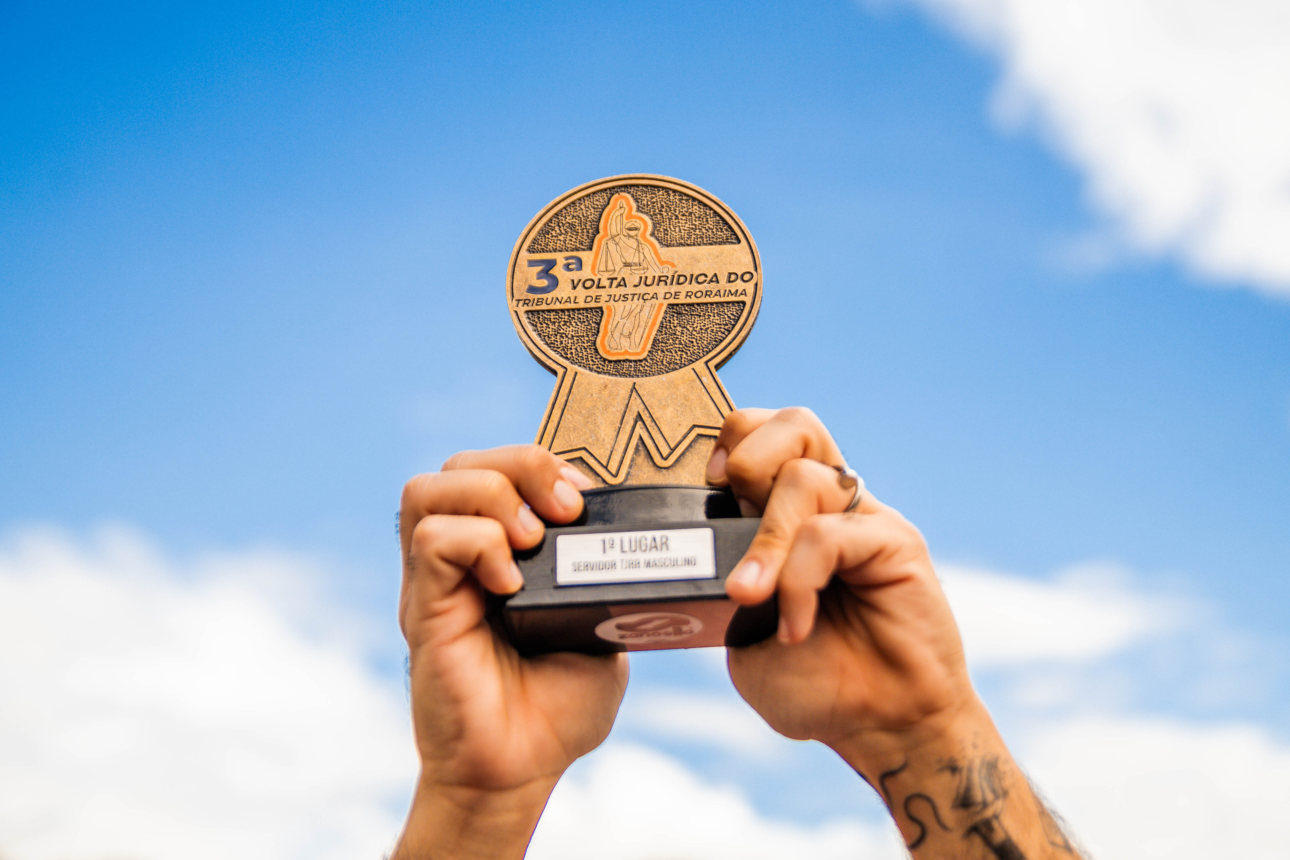 Foto colorida mostrando uma pessoa segurando o troféu da 3ª edição da corrida de rua 'Volta Jurídica Foto colorida mostrando uma pessoa segurando o troféu da 3ª edição da corrida de rua 'Volta Jurídica