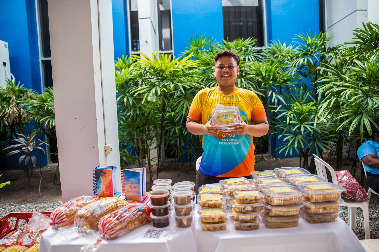 Foto colorida mostrando um representante da Fazenda esperança mostrando os produtos que serão vendidos na feira