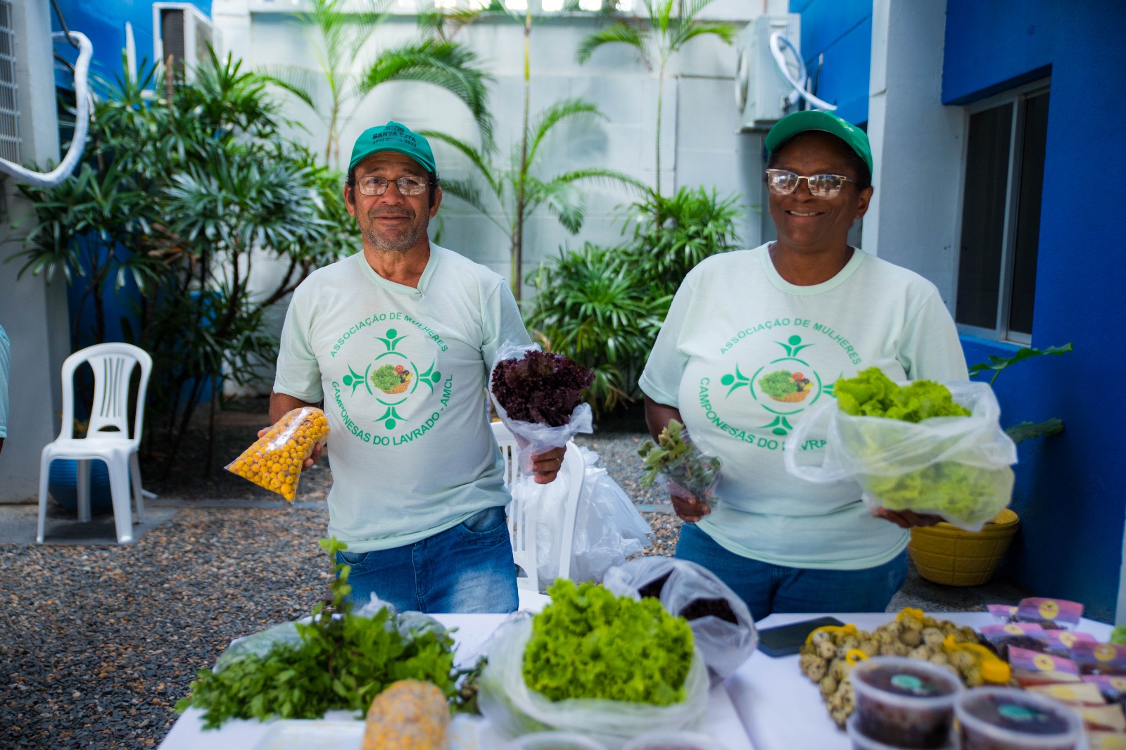 Foto colorida mostrando um representantes das Camponesas do Lavrado mostrando os produtos que são vendidos na feira