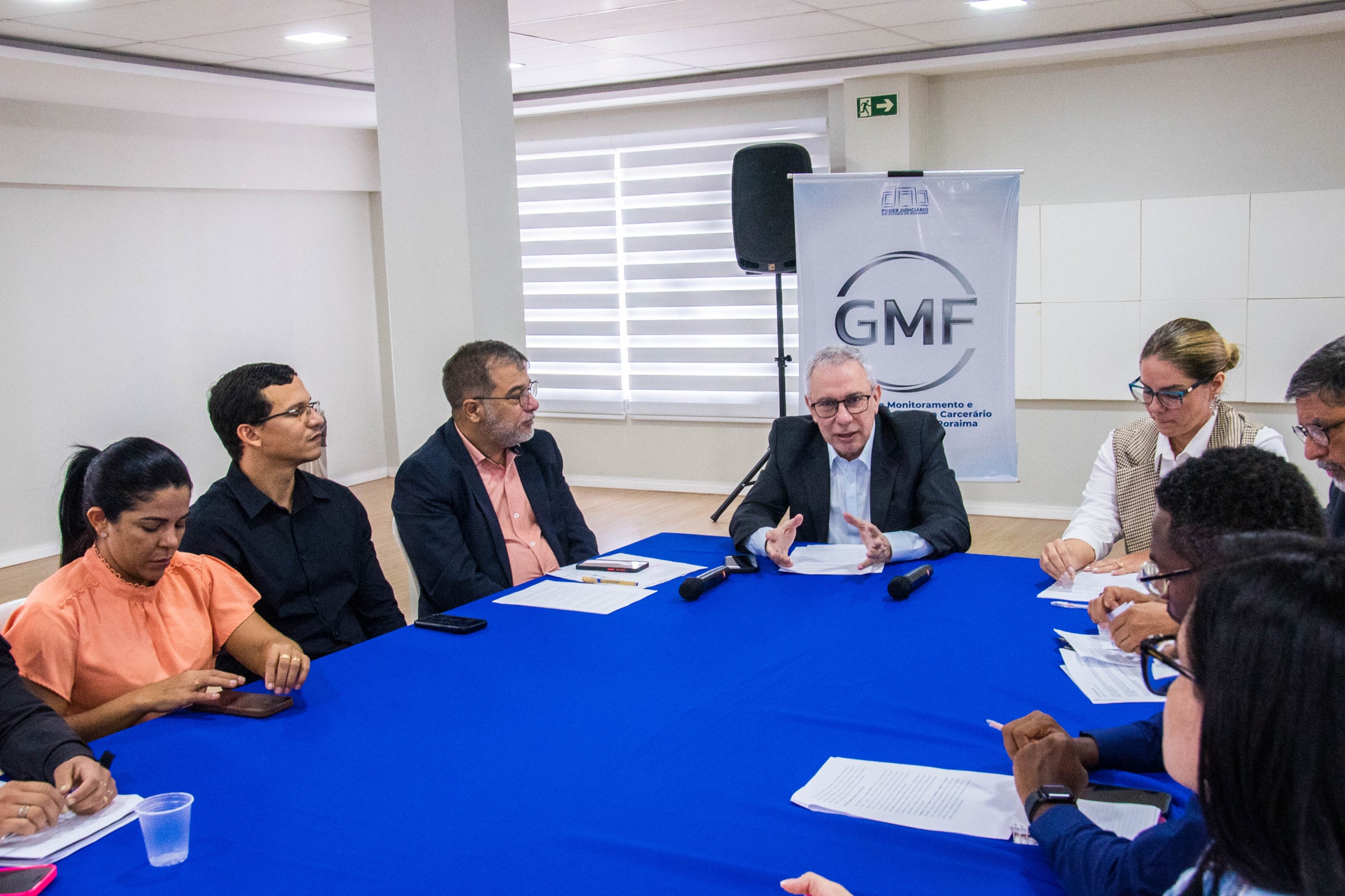 Imagem colorida contém o Supervisor do GMF/TJRR, Vice-presidente, Desembargador Almiro Padilha, sentado em mesa de reunião com mais 13 representantes de instituições privadas e públicas, para empregabilidade de pessoas egressas do sistema penitenciário.Atrás dele se encontra o banner do GMF/TJRR Imagem colorida contém o Supervisor do GMF/TJRR, Vice-presidente, Desembargador Almiro Padilha, sentado em mesa de reunião com mais 13 representantes de instituições privadas e públicas, para empregabilidade de pessoas egressas do sistema penitenciário.Atrás dele se encontra o banner do GMF/TJRR