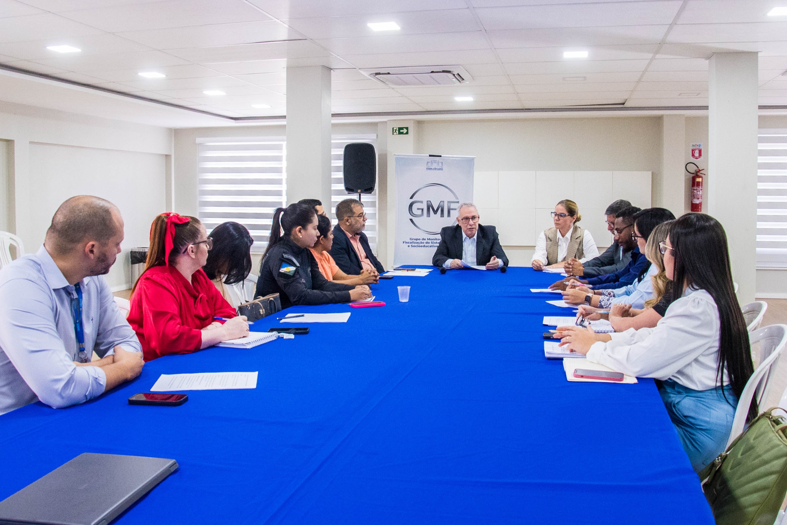 Imagem colorida contém o Supervisor do GMF/TJRR, Vice-presidente, Desembargador Almiro Padilha, sentado em mesa de reunião com mais sete representantes de instituições privadas e públicas, para empregabilidade de pessoas egressas do sistema penitenciário. Atrás dele se encontra o banner do GMF/TJRR