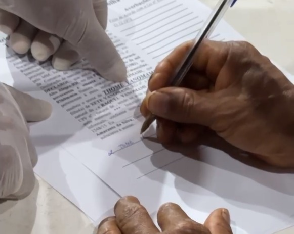 Imagem colorida de uma pessoa assinando um documento