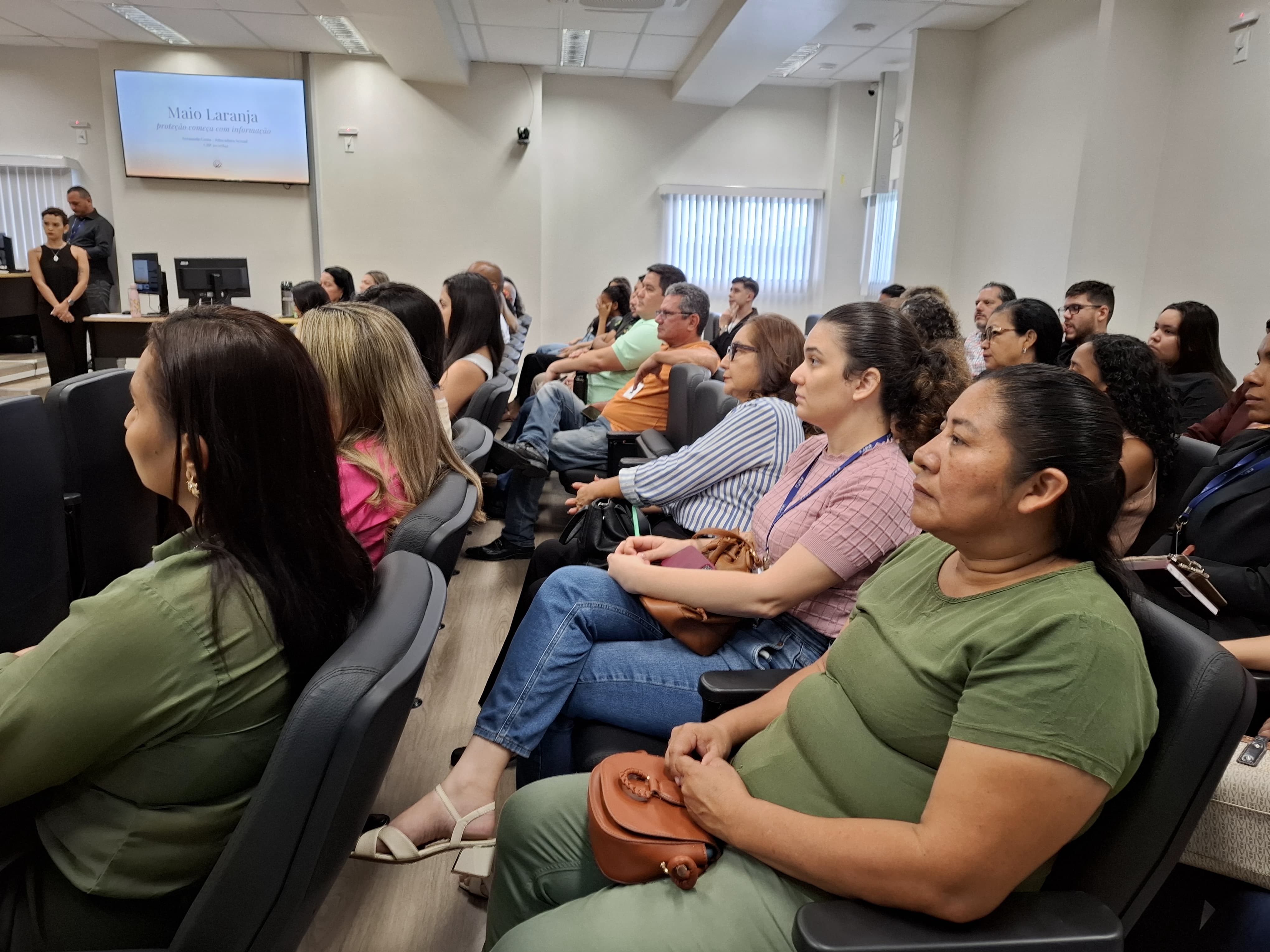 Imagem colorida mostra um auditório cheio, com diversas pessoas sentadas assistindo a uma palestra. Imagem colorida mostra um auditório cheio, com diversas pessoas sentadas assistindo a uma palestra.