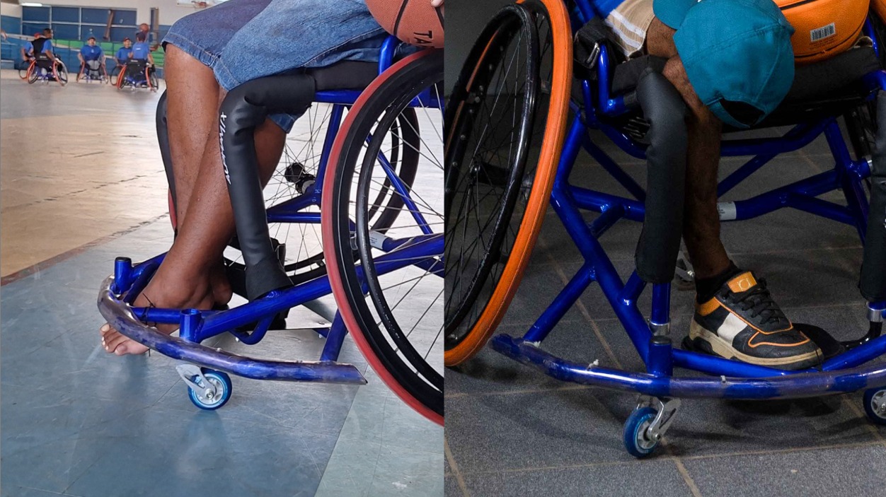 Foto colorida mostra um grupo diverso de atletas paralímpicos e apoiadores reunidos em uma sala do Centro de Referência Paralímpico de Roraima. Alguns estão em cadeiras de rodas, com bolas de basquete e tênis de mesa. Ao fundo, há banners e uma grande faixa azul na parede com o nome do centro.