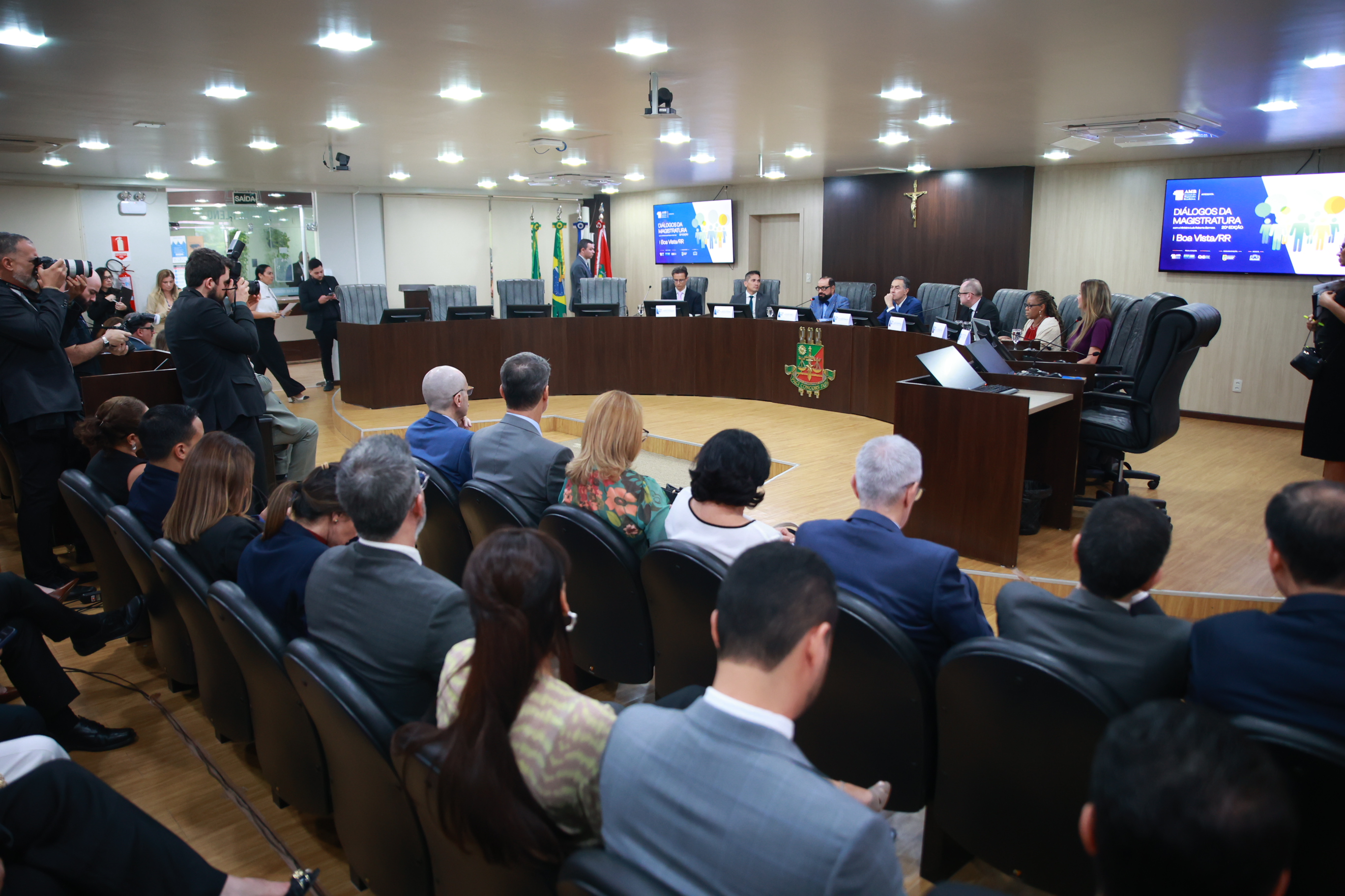 Imagem colorida em plano aberto do Tribunal Pleno durante a cerimônia do "Diálogos da Magistratura com o Ministro Luís Roberto Barroso”. Ao fundo é possível ver a mesa de autoridades composta pelo presidente do TJRR e pela comitiva do presidente do STF E CNJ.