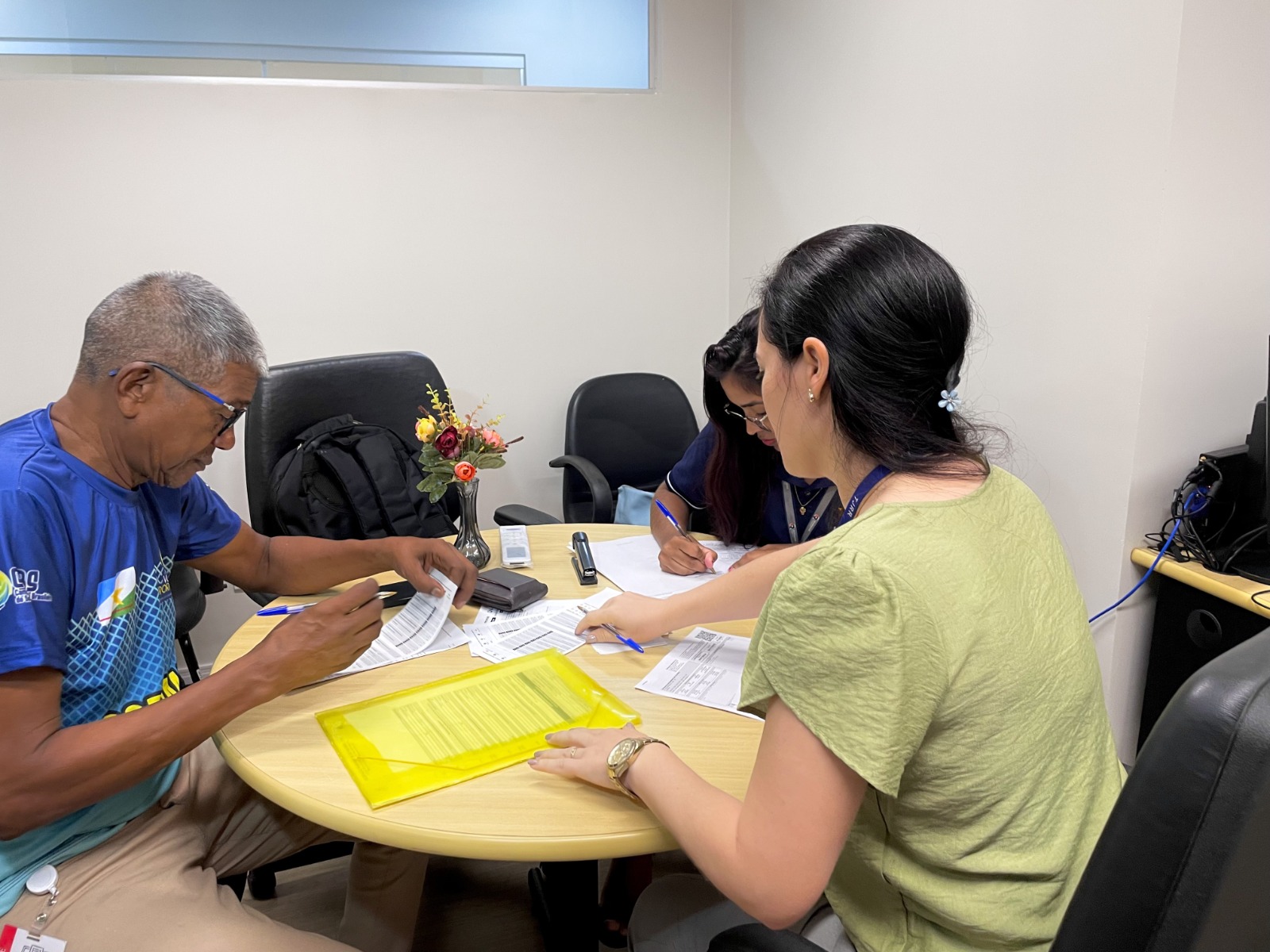 Imagem colorida durante um atendimento, Há duas mulheres na foto, uma da empresa de energia e outra do TJRR e um homem.