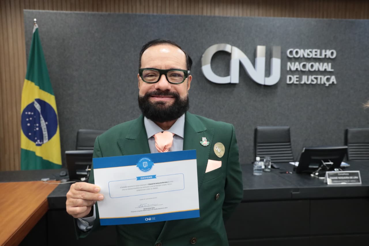 imagem colorida mostra o presidente do TJRR, desembargador Leonardo Cupello segurando certificado de linguame simples do CNJ.