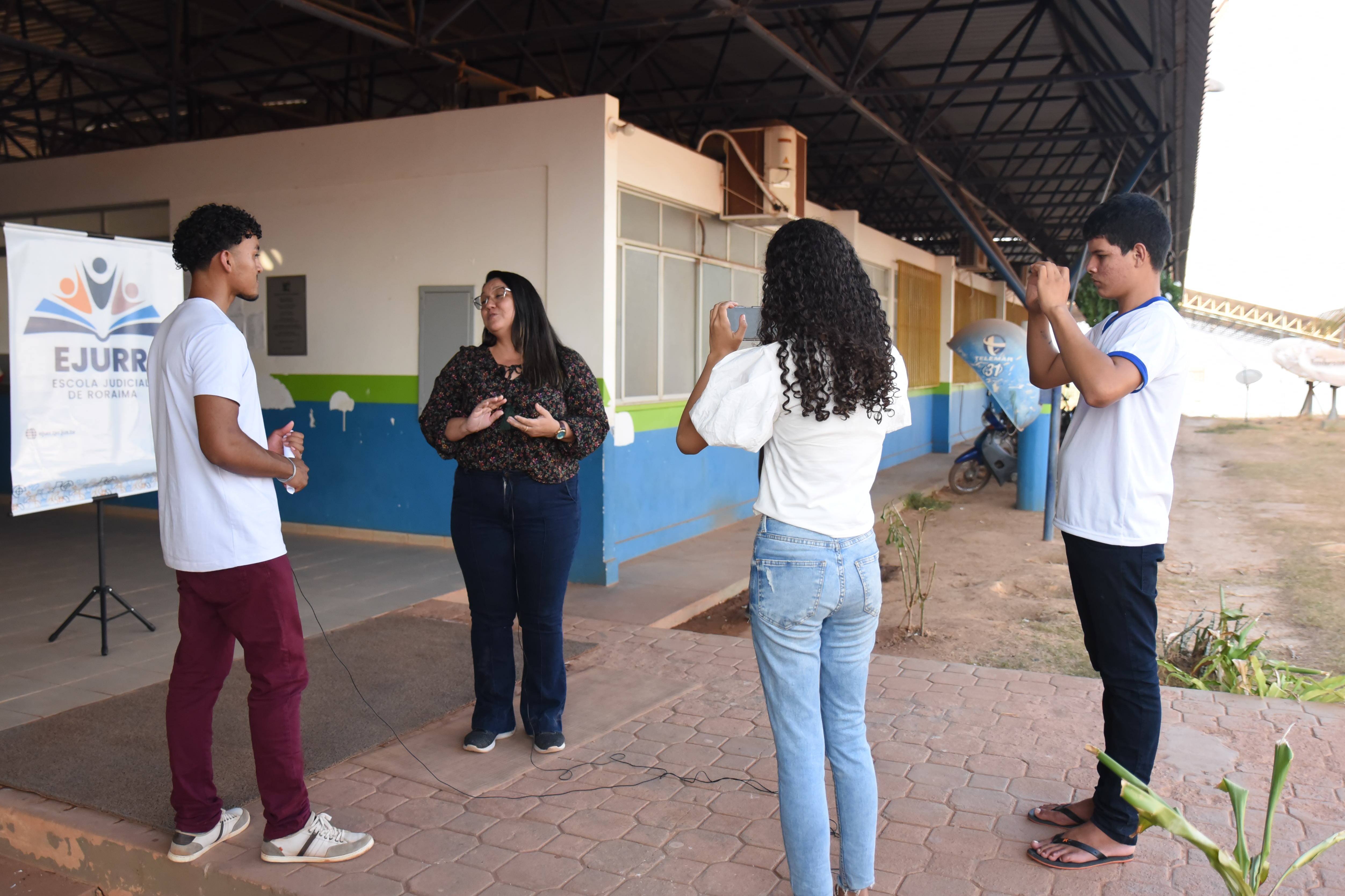 Imagem colorida mostra alunos e representante da Escola Estadual Joaquim Nabuco realizando entrevista para os vídeos gravados.