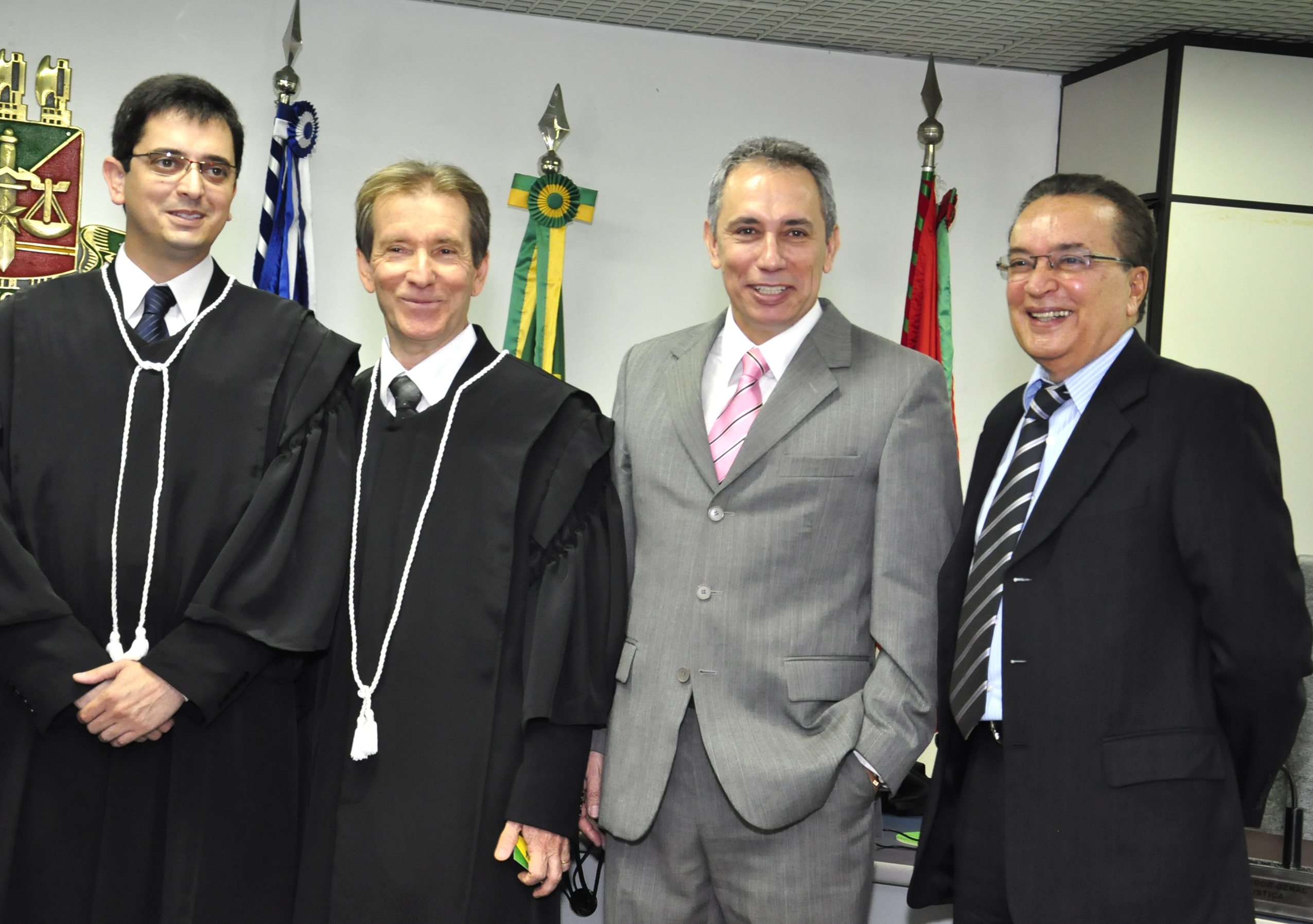 Foto colorida mostra 4 magistrados em pé posando para foto.