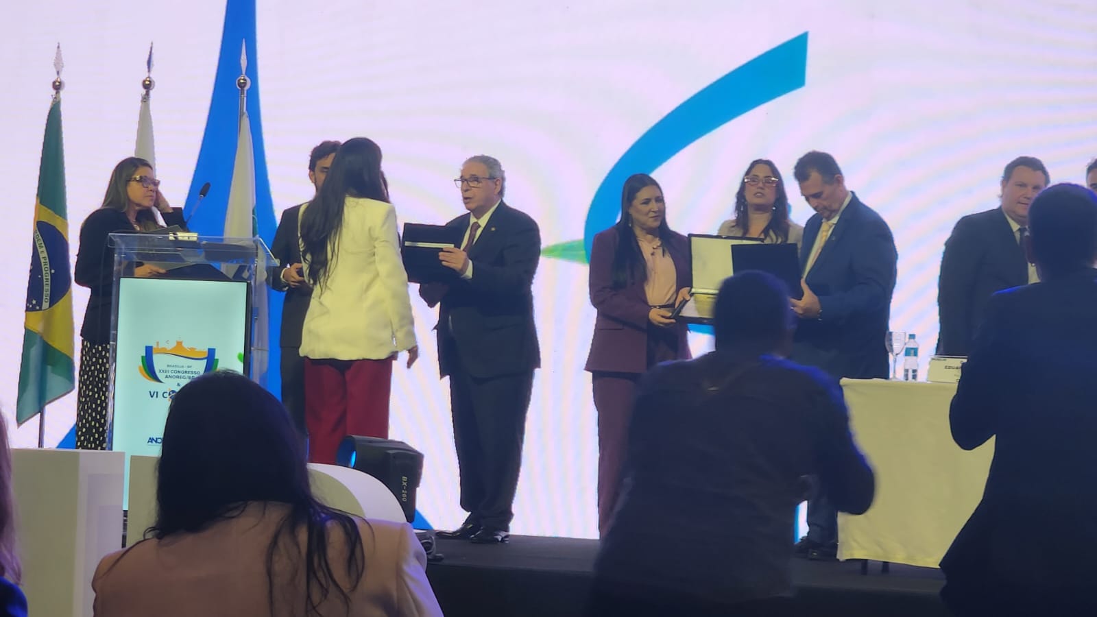 Foto colorida mostra a servidora do TJRR, Luciana Menezes segurando premiação em homenagem ao desembargador Mozarildo Cavalcanti, durante congresso nacional Anoreg/BR.
