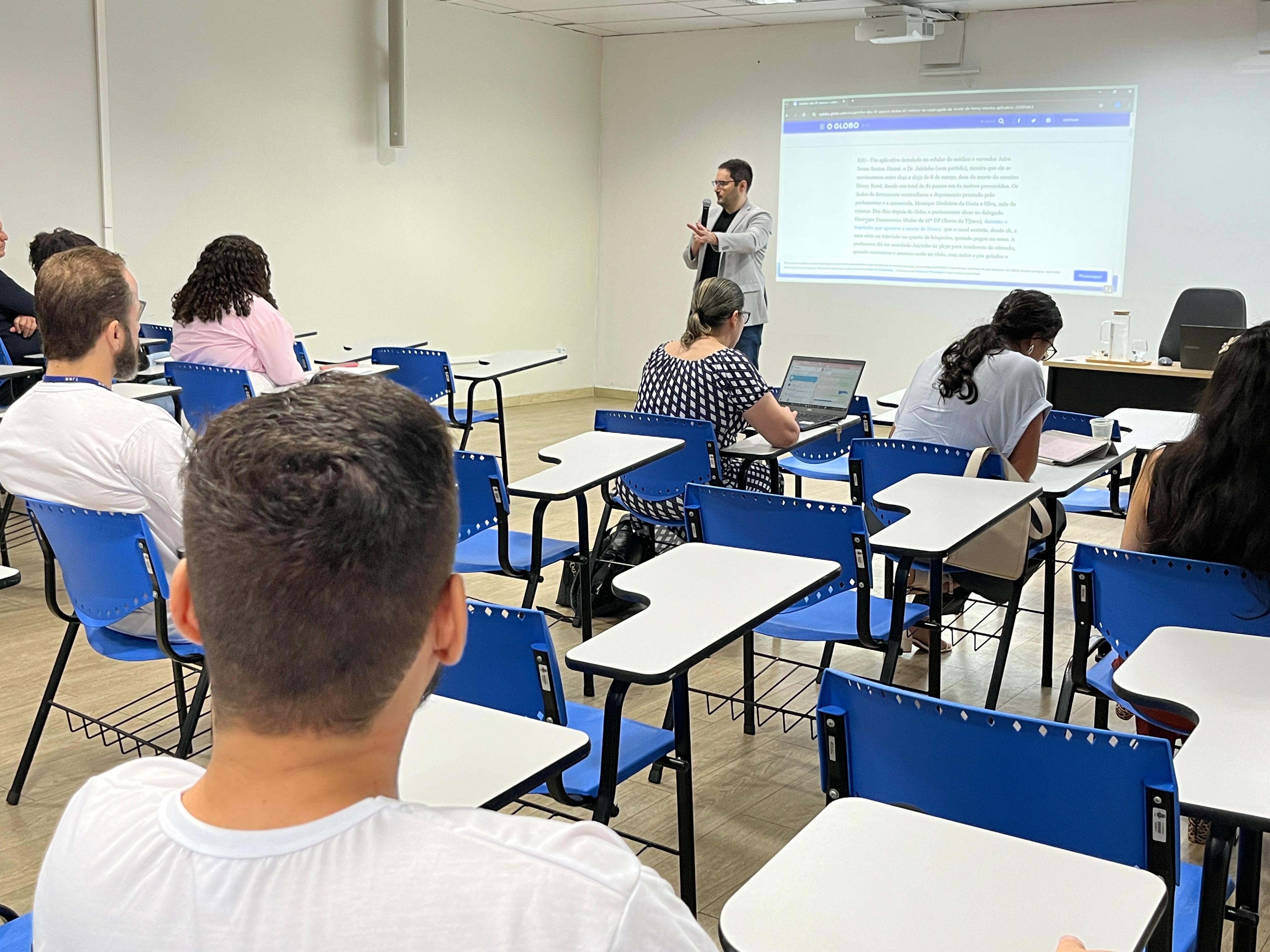 foto colorida de uma sala com cadeiras escolares ocupadas por servidores e ministrando a palestra o especialista Bernardo de Azevedo