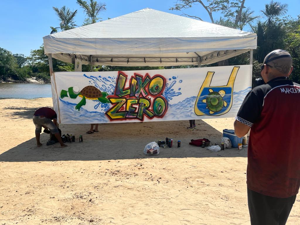 foto colorida de uma tenda na praia com uma arte escrita lixo zero