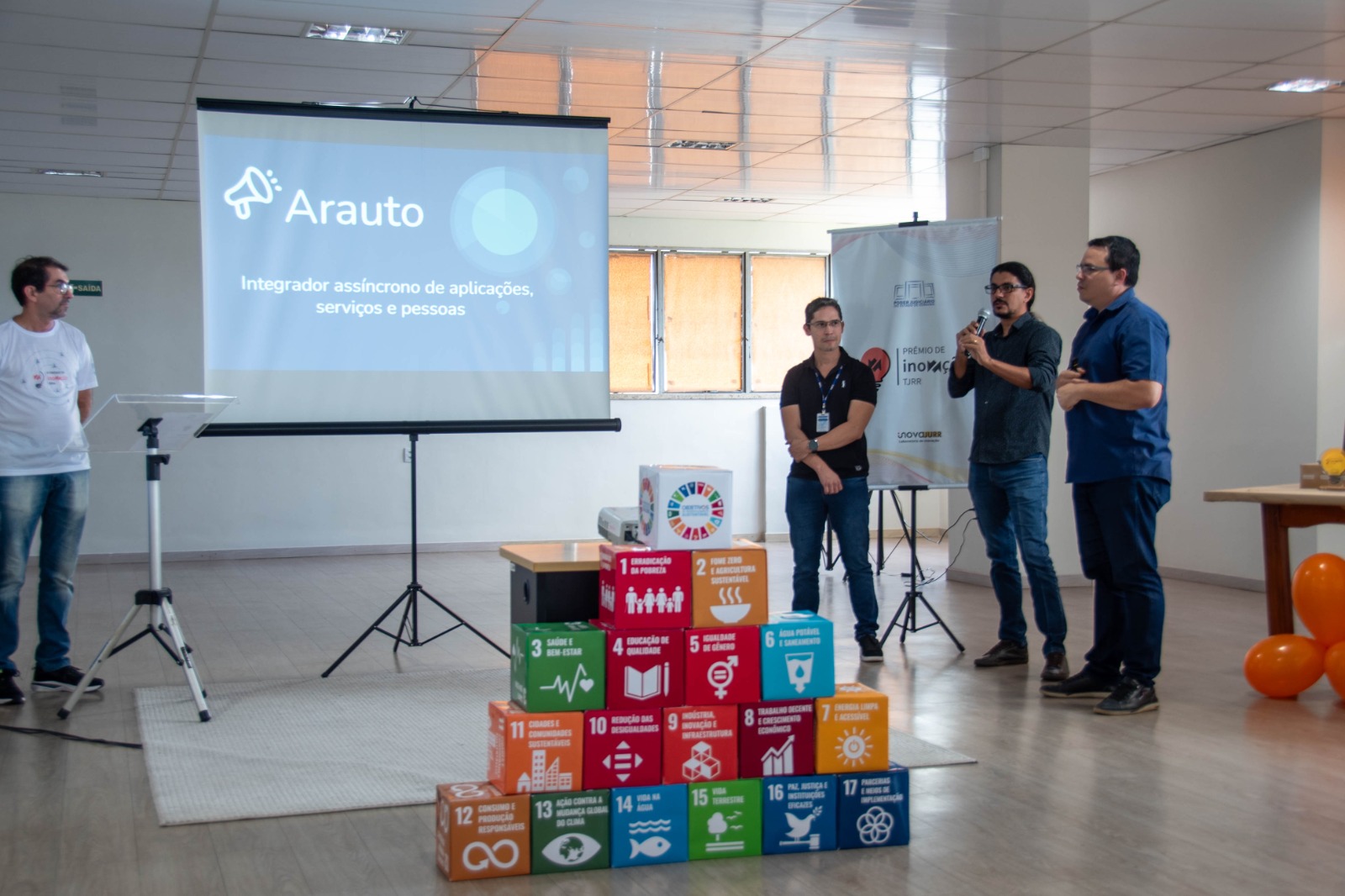 foto colorida de uma equipe composta por três homem apresentando o projeto 