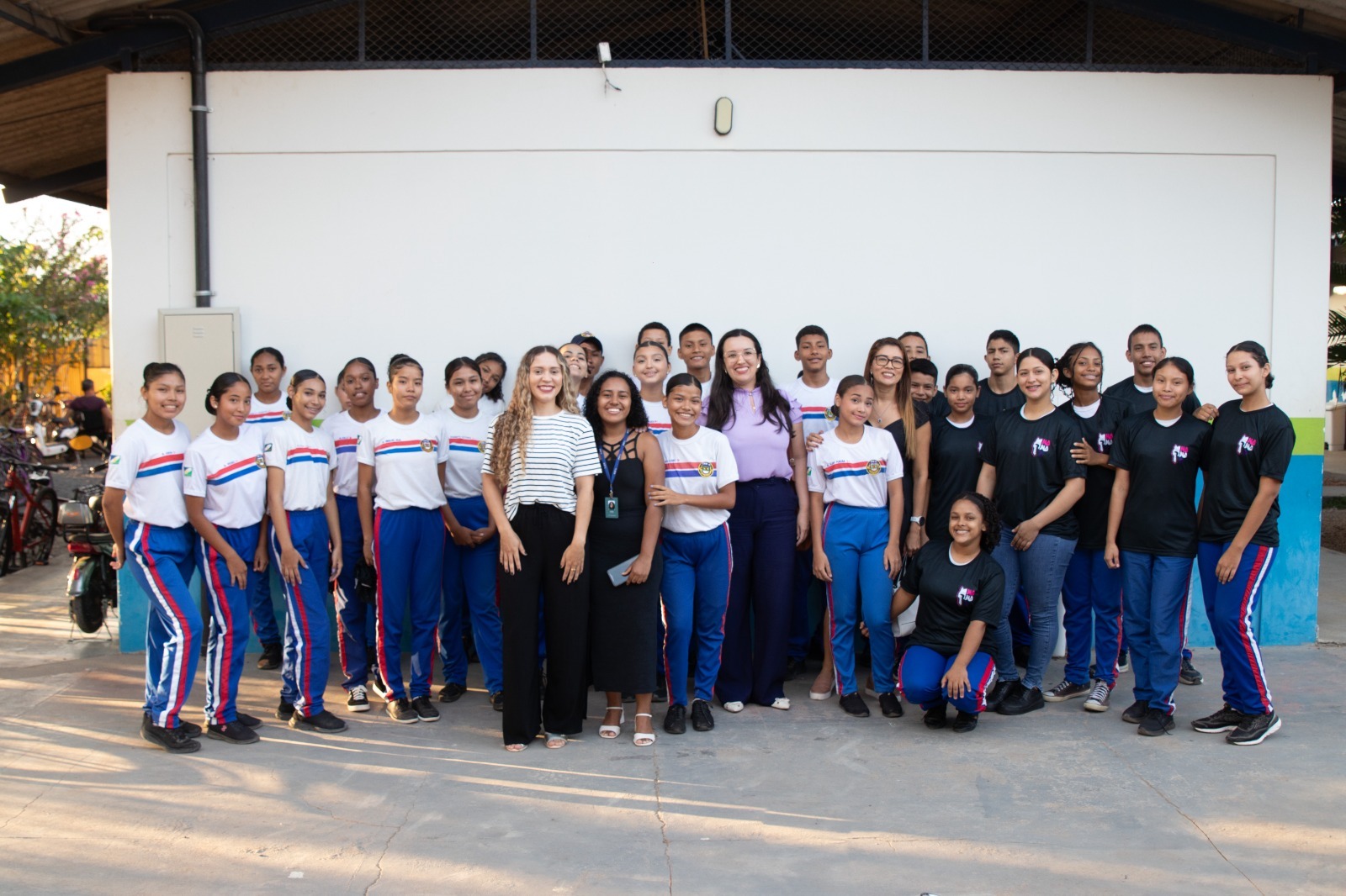 A imagem colorida mostra integrantes da ação de 21 dias ao lado de alunos do ensino fundamental, perfilados para foto