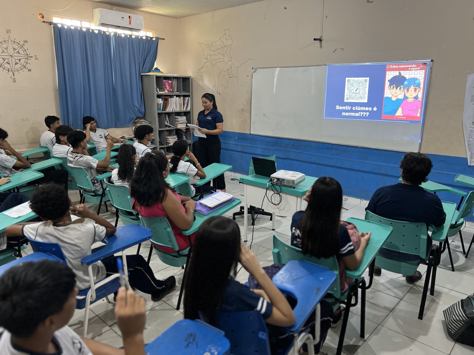 A imagem colorida mostra uma participante dos 21 dias em palestra sobre a cartilha "Tô Namorando, e agora?" para alunos do ensino fundamental.