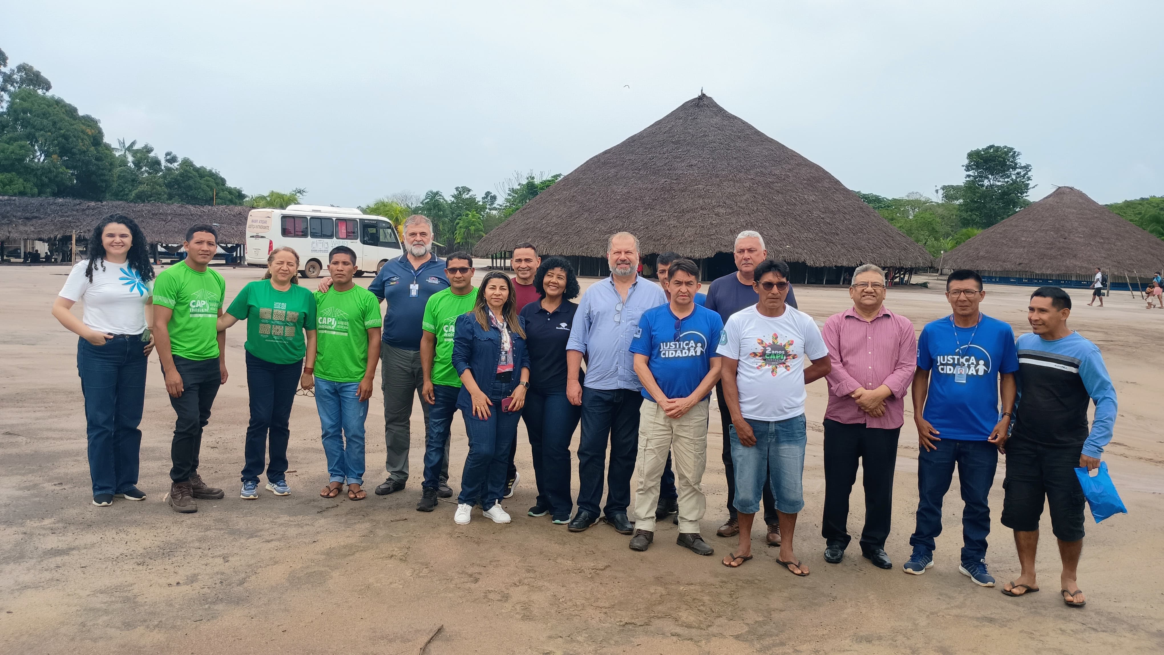 Imagem colorida mostra servidores da Ouvidoria-Geral do Tribunal de Justiça de Roraima e representantes da Terra Indígena Waimiri-Atroari posando para foto em área externa da comunidade Indígena Waimiri-Atroari, entre eles se destacam o servidor da Ouvidoria-Geral do Tribunal de Justiça de Roraima, Amadeu Triani, além da representante da representante da Escola Judicial de Roraima, Tatiana Saldanha. Abaixo a frase “CIDADANIA - Ouvidora do TJRR realiza atendimento aos povos originários da T.I. Waimiri-Atroari”.
