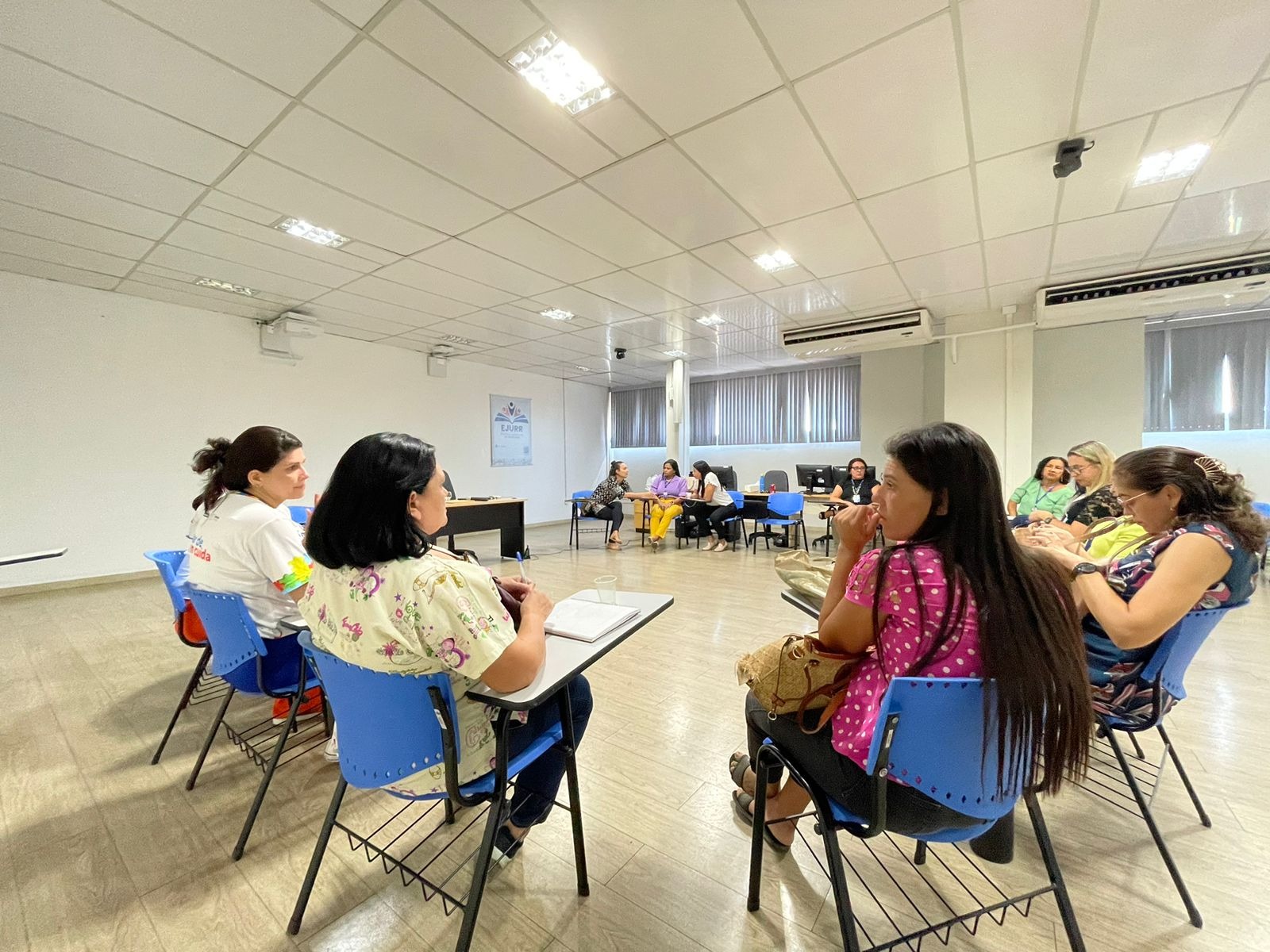 foto colorida mostra uma sala com várias mulheres sentadas em circulo conversando