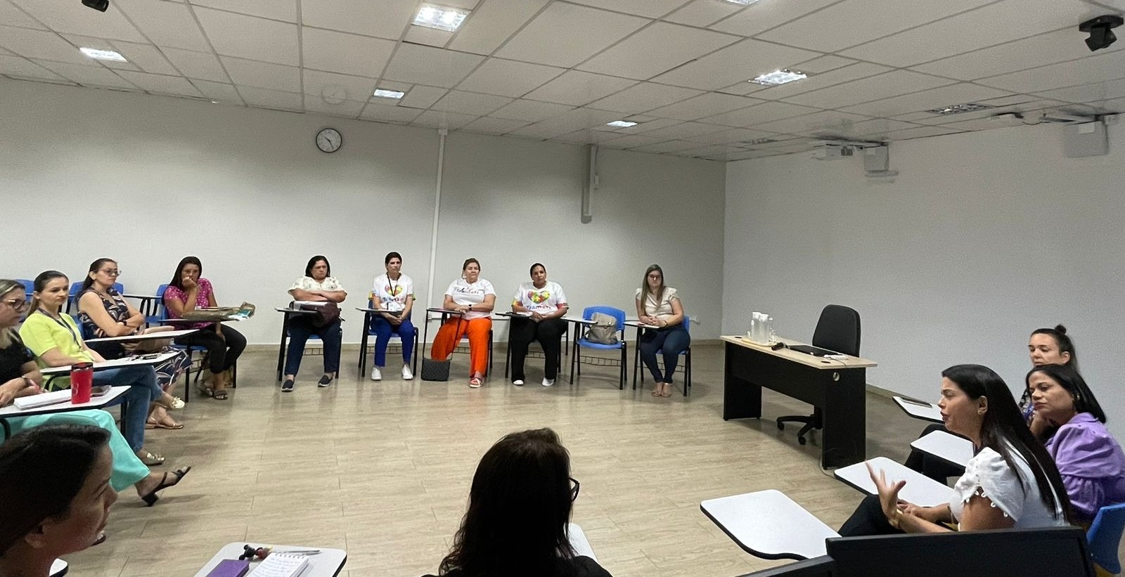 foto colorida mostra uma sala com várias mulheres sentadas em circulo conversando