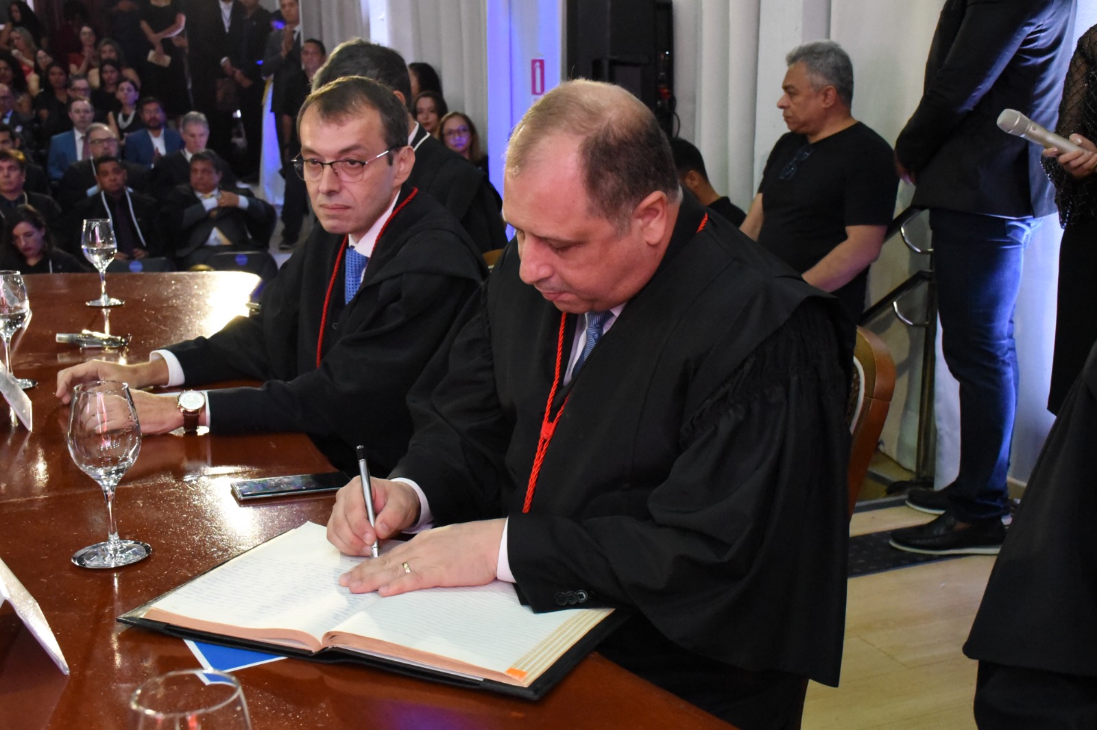 Imagem colorida mostra o corregedor-geral do Tribunal de Justiça de Roraima, desembargador  Mozarildo Cavalcanti, assinando o termo de posse.