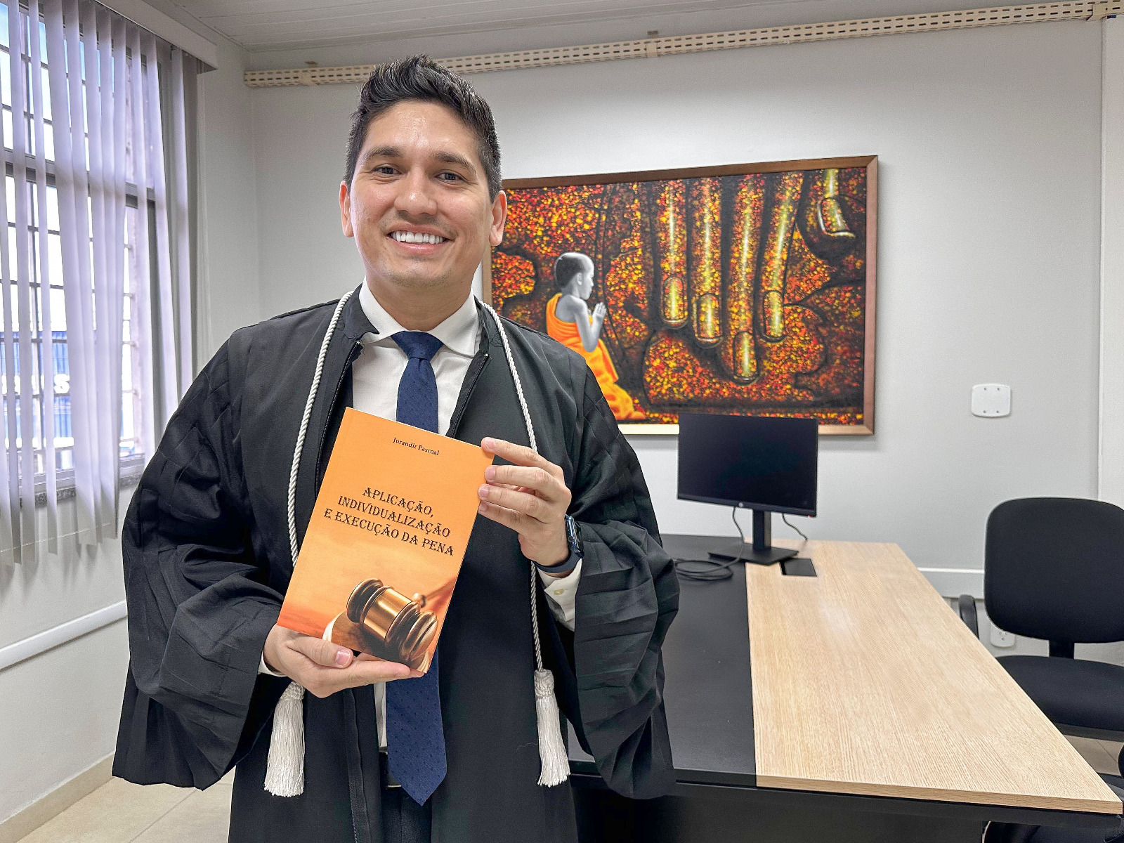 foto colorida de um juiz segurando o livro do desembargador aposentado, Jurandir pascoal