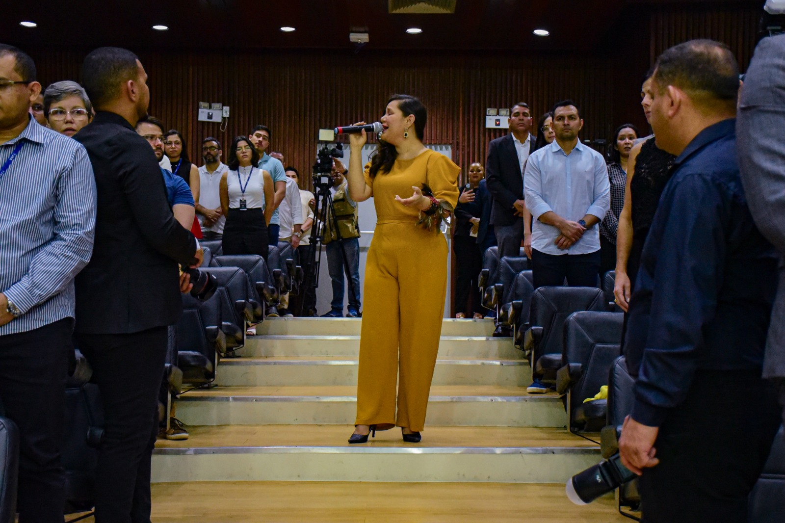foto colorida de uma mulher vestida de amarelo cantando