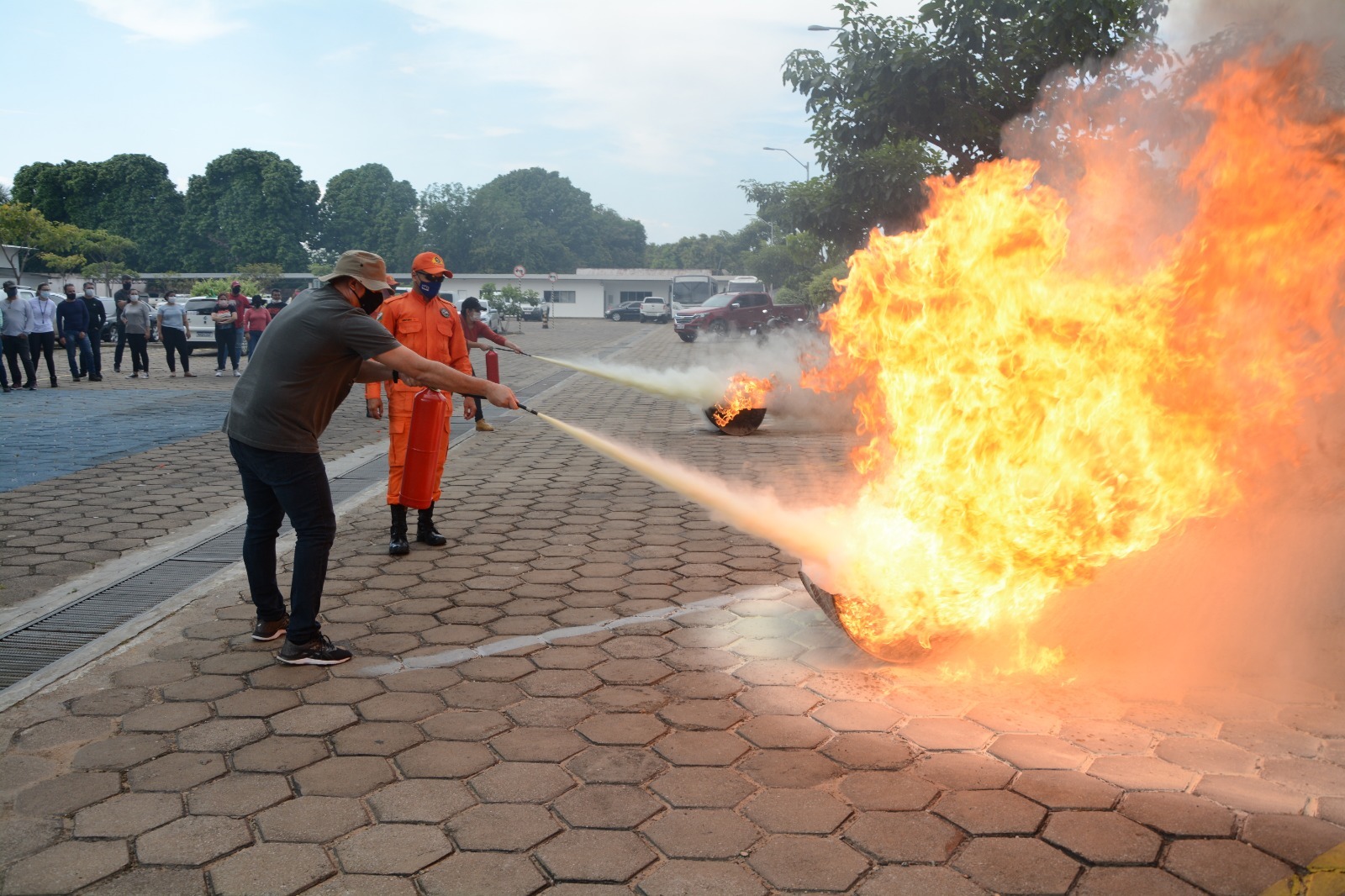 foto colorida de um servidor realizando o treinamento apagando fogo e ao lado há um bombeiro