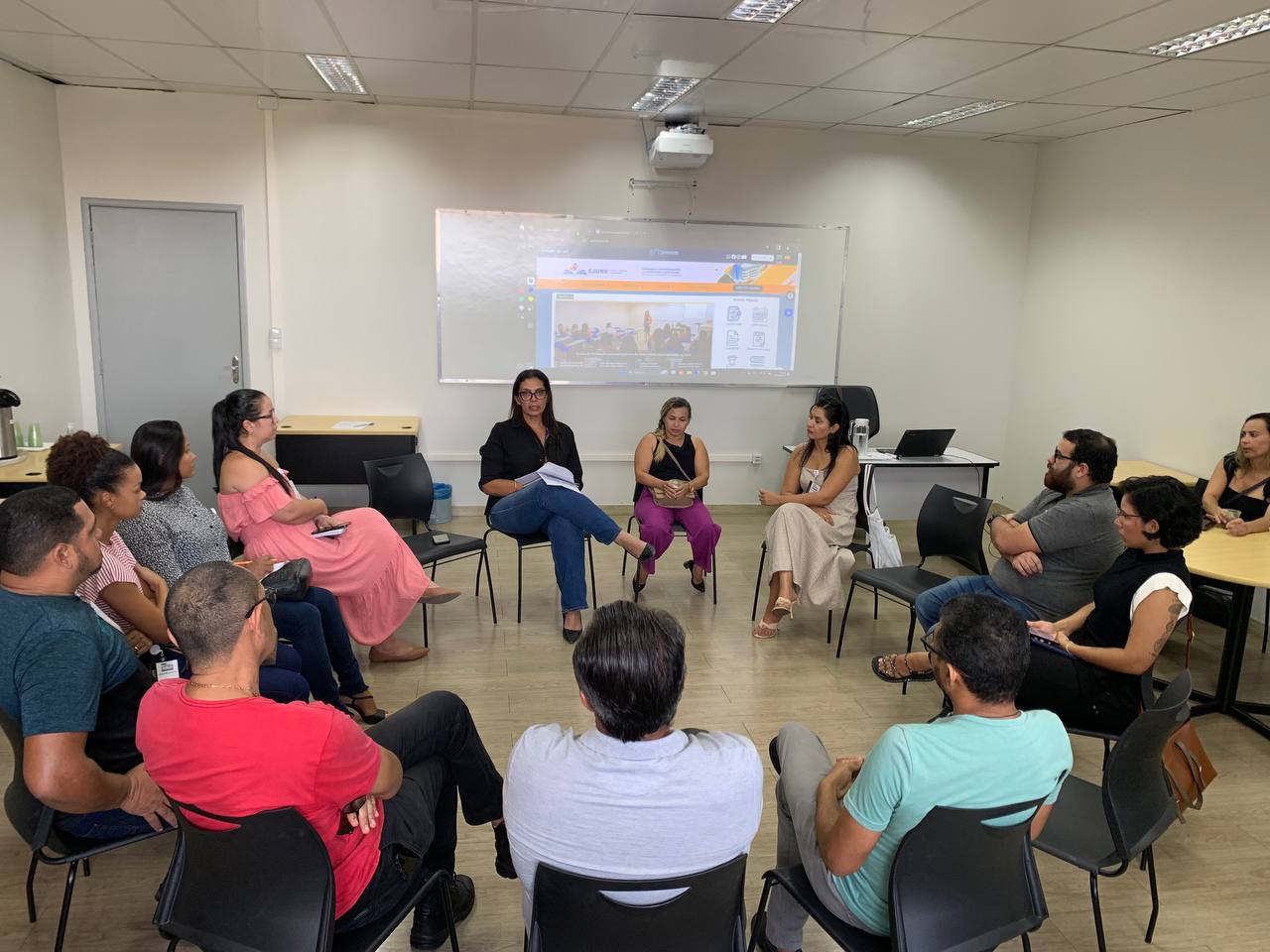 Foto colorida mostra 13 pessoas em uma roda de conversa, entre eles a chefe da unidade de Justiça Restaurativa (UNIJUR), Valeska Carvalho.