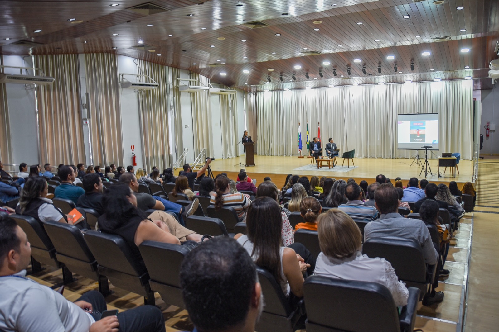 foto colorida de pessoas assistindo uma palestra no auditório do fórum cível