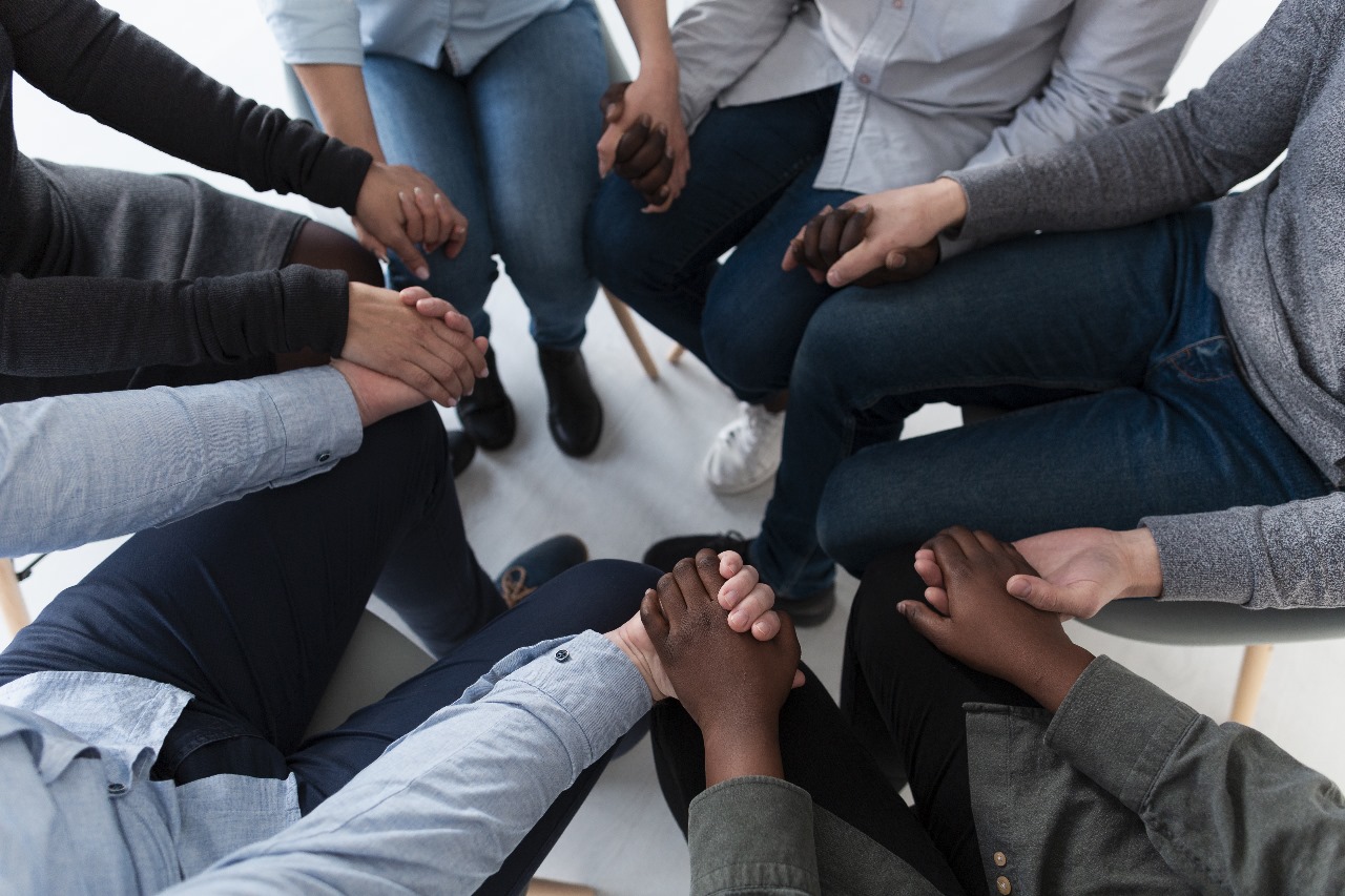 Imagem mostra pessoas em uma roda dando as mãos uns para os outros