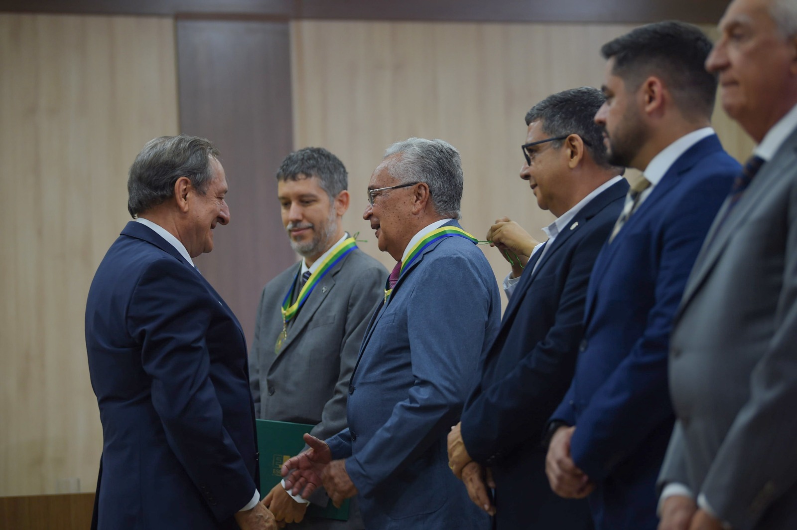 to colorida mostra seis pessoas reunidas durante o recebimento da medalha de honra, no qual na entre eles está o desembargador Lupercino Nogueira, magistrado aposentado do TJRR, recebendo a Medalha de Mérito Acadêmico da Escola Judicial do Justiça do Amazonas